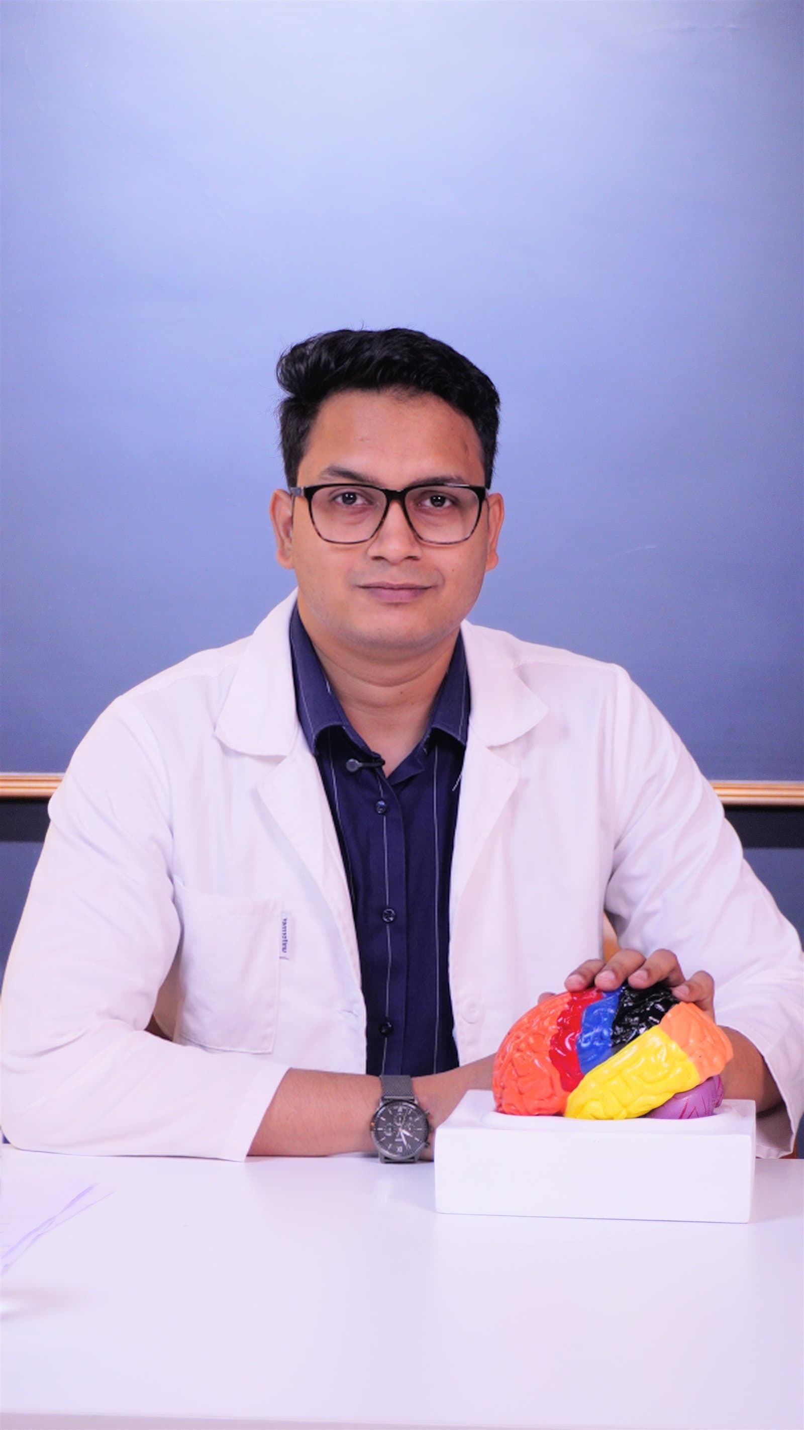 Dr. Abhijeet Holambe in his clinic holding a brain model